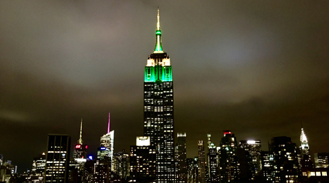 The Empire State Building at night with green and gold uplighting