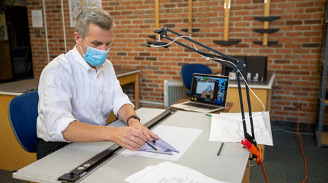 Matthew Allar draws at a drafting table with camera overhead