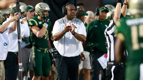 Mike London clapping his hands on the football field sideline