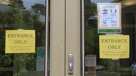 Signs outlining safety protocols hang on a door on campus