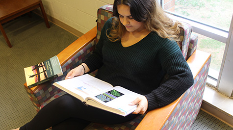 Student reads textbook at library
