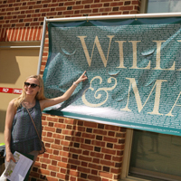 A students points to a large William & Mary sign