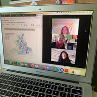 Laptop with screen showing graphic of Virginia map on left side and three women videoconferencing on right side