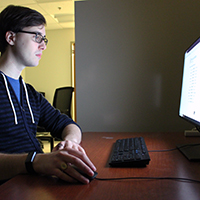 Garret Walker, class of 2019, sits in front of a computer in the lab that he manages