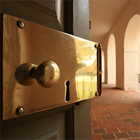 A door with a brass lock is ajar, and the Wren portico can be seen in the background