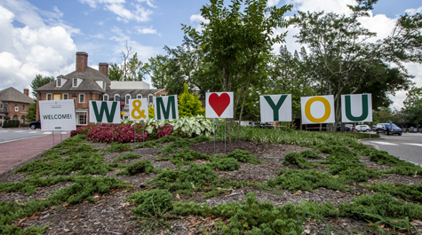 Signs in a flower bed spell out Welcome, W&M Loves You