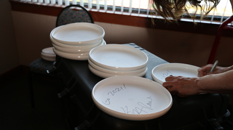A person signs the back of frisbees with Go 2021