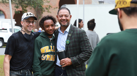Three people stand together for a photo outside