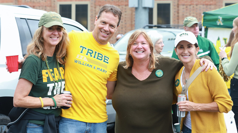 People wearing green and gold clothing stand together for a photo