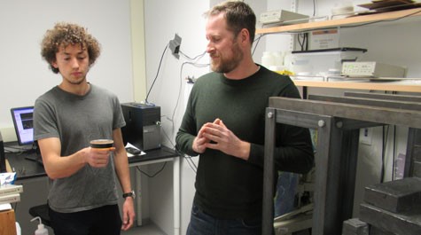 Two people stand in a lab and one holds a circular disc