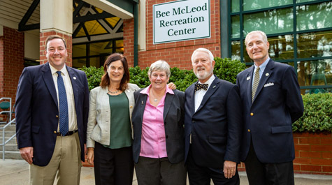 Several people stand in front of a brick building with a sign on it that says Bee McLeod Recreation Center