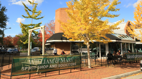 A brick building on a street corner with signs on the fence that say grand opening and W&M spirit shop and bookstore 