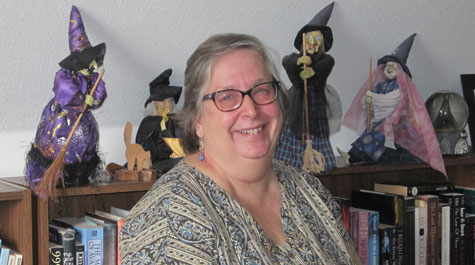 Barbette Spaeth with witch dolls on shelf behind her