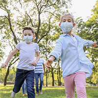 Children in face masks play outdoors