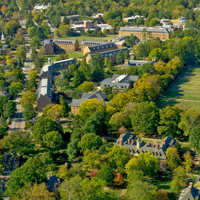 An aerial view or campus shows brick buildings, trees and green spaces