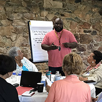 A group of people meeting and discussing at a table and taking notes