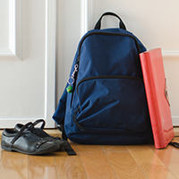 Backpack and children's shoes lean against door