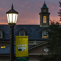 Sunset on campus with a sign that reads "Masks Up"