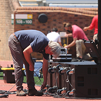A person rigs up audio and video lines inside Zable Stadium