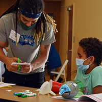Miguel Jones, a sophomore at W&M, works with one of the EAGER campers to build a rocket made from a soda bottle.  