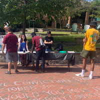 Innocence Club members tabling and chalk message on bricks