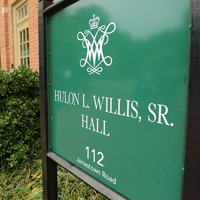 A green, outdoor sign that says Hulon L. Willis Sr. Hall 112 Jamestown Road