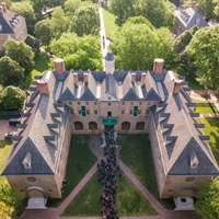 An aerial view of a large brick building with people on a pathway leading to it