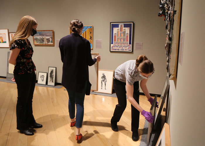 Students arrange artwork as part of choosing, writing text for and displayng Leonard Baskin works in the Muscarelle Museum of Art galleries as part of the Curatorial Project exhibition. (Photo by Stephen Salpukas)