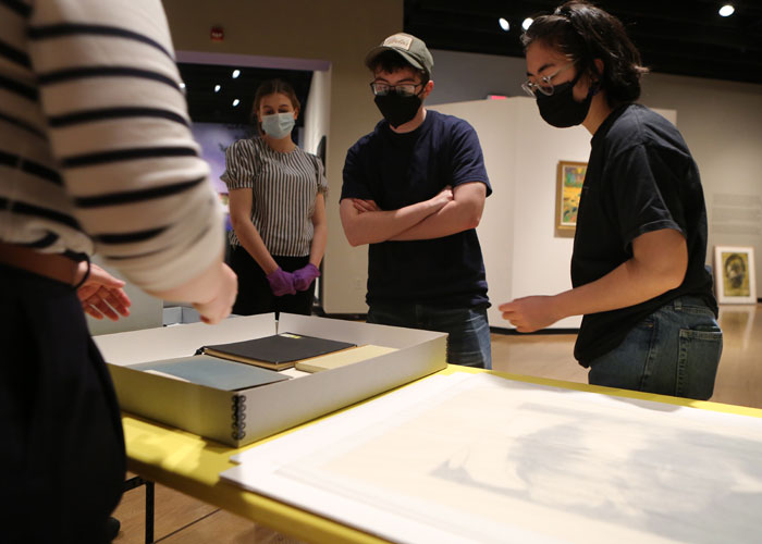 Students look over works from University Libraries Special Collections that will be part of the exhibition. (Photo by Stephen Salpukas)