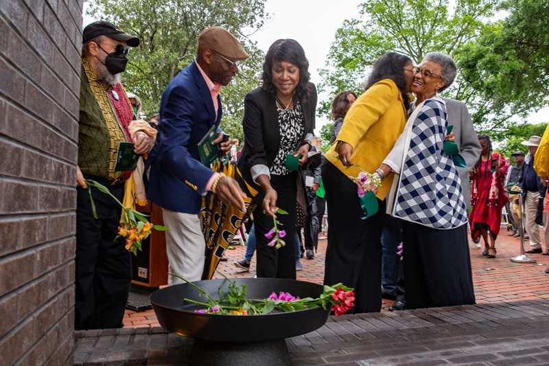     Participants in the ceremony place flowers in a basin at the base of the memorial. (Photo by Skip Rowland '83)