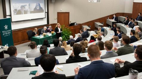 Four people sit at a table at the front of a classroom full of people