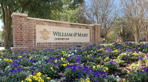 A brick sign that says William & Mary sits in a bed of flowers
