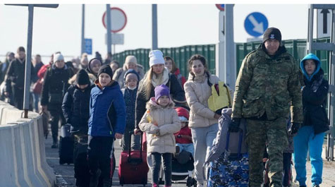 A crowded line of Ukranian people carrying luggage dressed in winter coats and hats