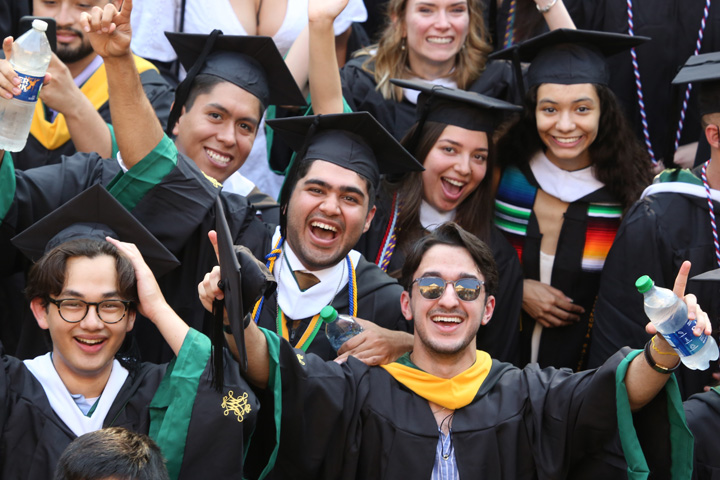 People wearing academic regalia smile for a photo together