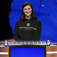 Lucy Greenman standing at the Jeopardy! podium on set