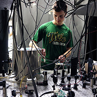 A student adjusts lenses on a quantum optics table