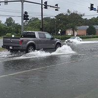 A truck drives through a flooded intersection