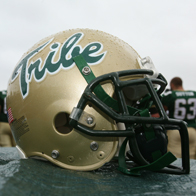 A gold Tribe football helmet with rain drops on it