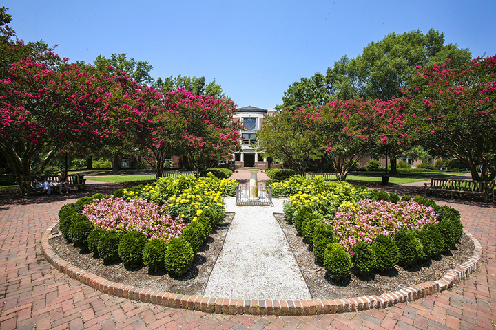 The sundial garden in front of Swem with flowers and trees blooming in multiple colors