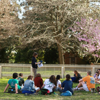 A professor stands among seated students in an outdoor location on campus