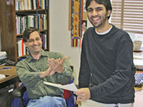 Rastogi looks over the score on his GRE as Carone applauds. By Joe McClain.