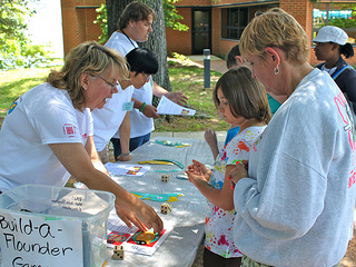 VIMS volunteer Diane Richmand, grad student Jennifer Elliott, and volunteer Tyler Kelley help visitors build a flounder during Marine Science Day.