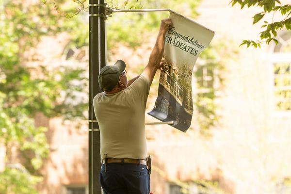 Facilities staff member removing banner from pole