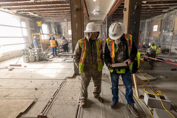 Two construction staff members reviewing blueprints in a construction zone