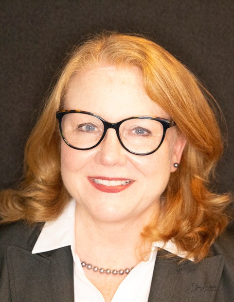 Teresa Belback wearing glasses and smiling into camera.