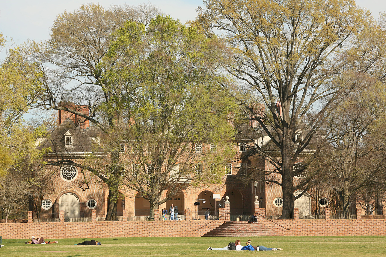 Trees bloom around the Wren Building while students lay in grass 