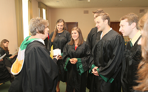 Baccalaureate grads have a quick discussion with a professor before the ceremony