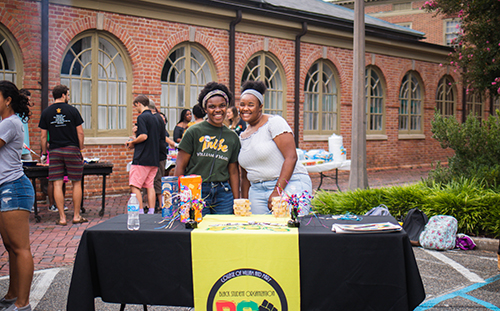 Students pose behind a table with information about joining the Black Student Organization