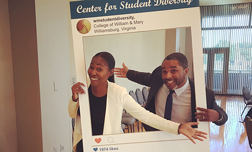Two students smile in a cardboard instagram cutout.