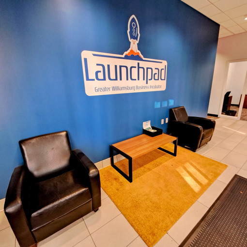 Comfortable leather chairs in a waiting area with Launchpad logo on a blue wall